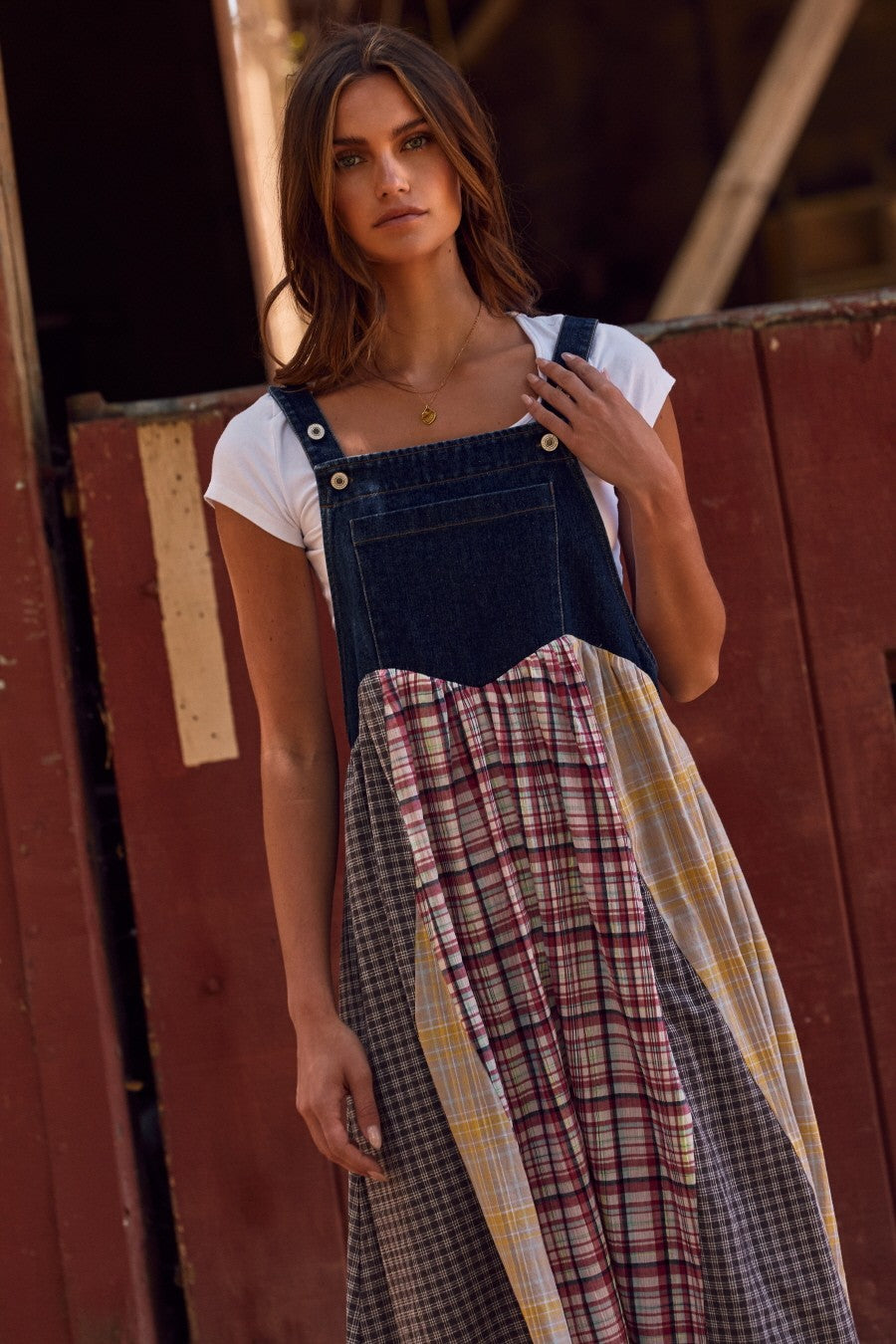 woman wearing a denim and plaid mix overall dress over a white t-shirt