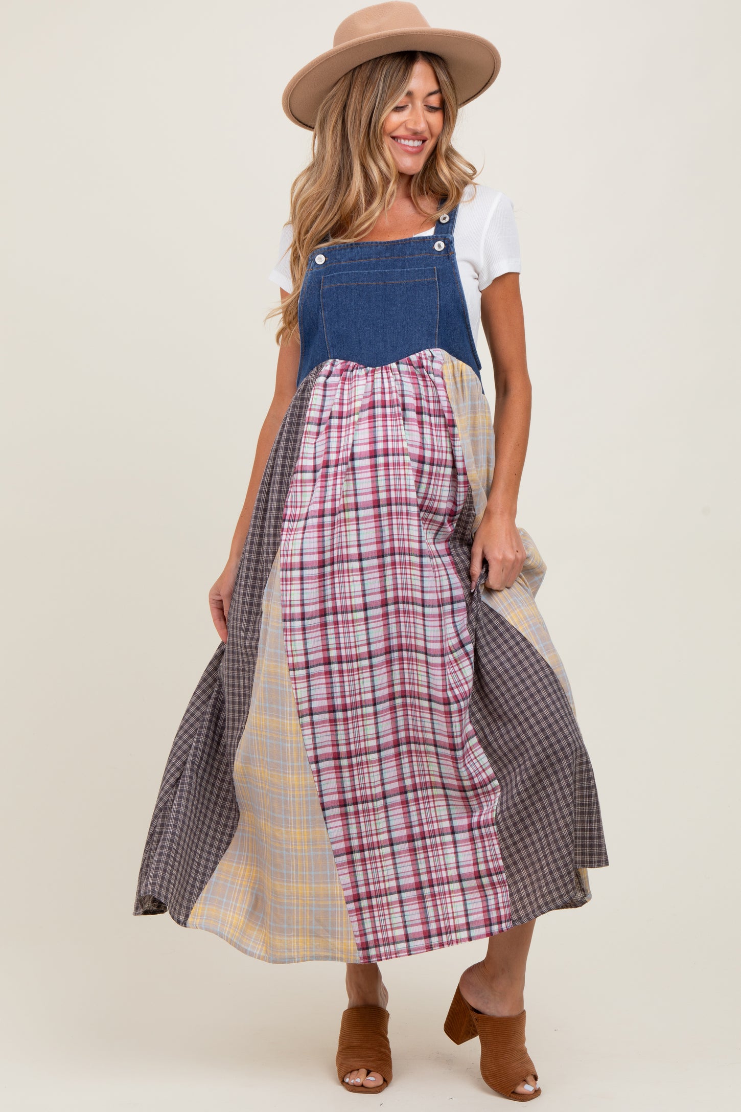 woman wearing a denim maternity maxi dress with a plaid skirt and a wide-brimmed hat, showing her baby bump