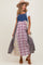 woman wearing a denim maternity maxi dress with a plaid skirt and a wide-brimmed hat, showing her baby bump