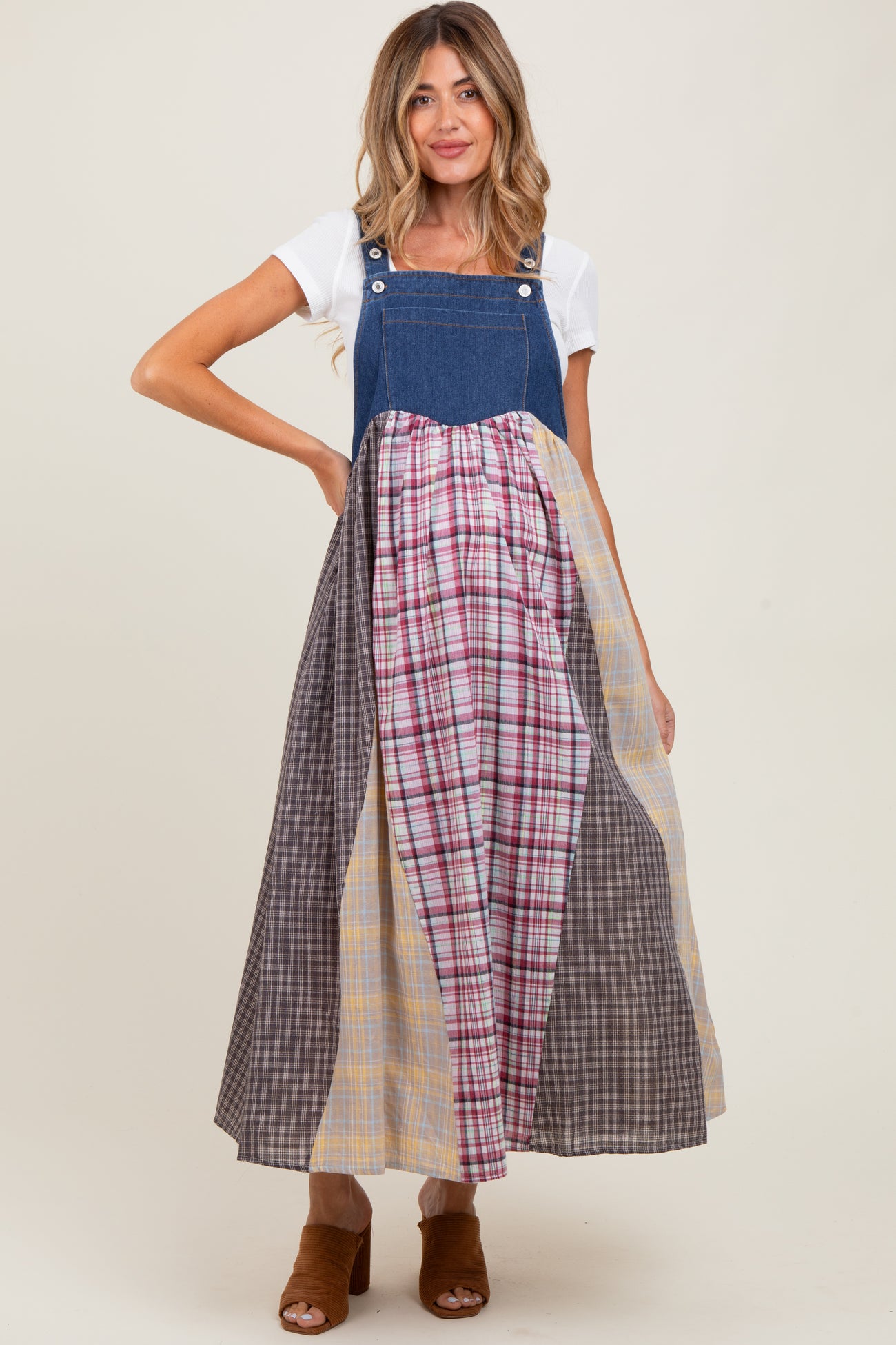 woman wearing a denim maternity maxi dress with a patchwork skirt of various plaid patterns and a white t-shirt underneath