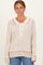woman wearing a cream and brown striped sweater with a collar and button details
