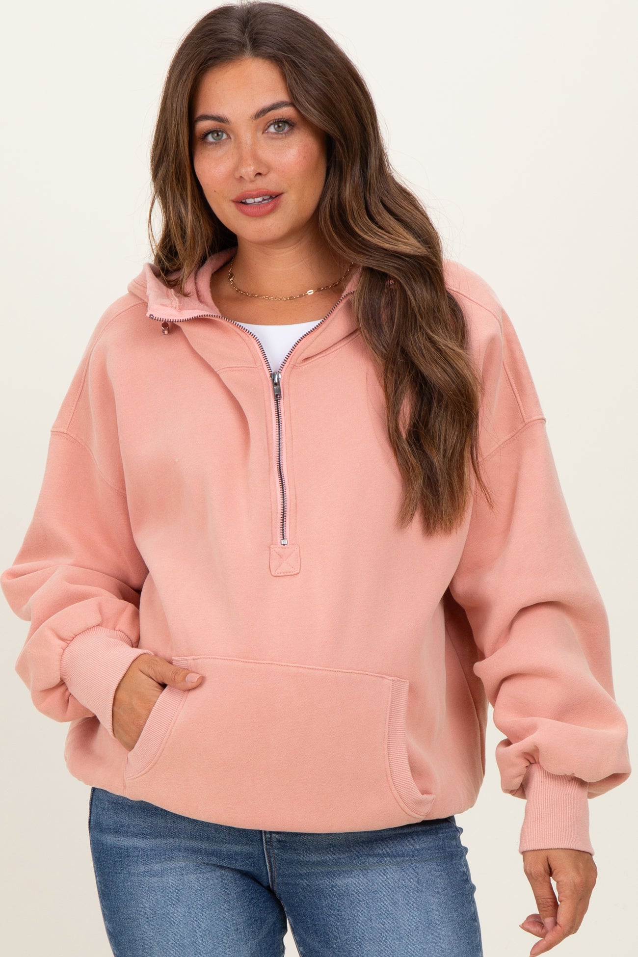 woman wearing a light pink zip-up maternity hoodie with long sleeves and a relaxed fit