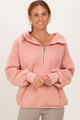 woman wearing a pink zip-up hoodie with a front pocket and loose sleeves, smiling at the camera