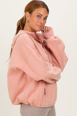 woman wearing a oversized blush pink zip-up hoodie with a relaxed fit and kangaroo pocket