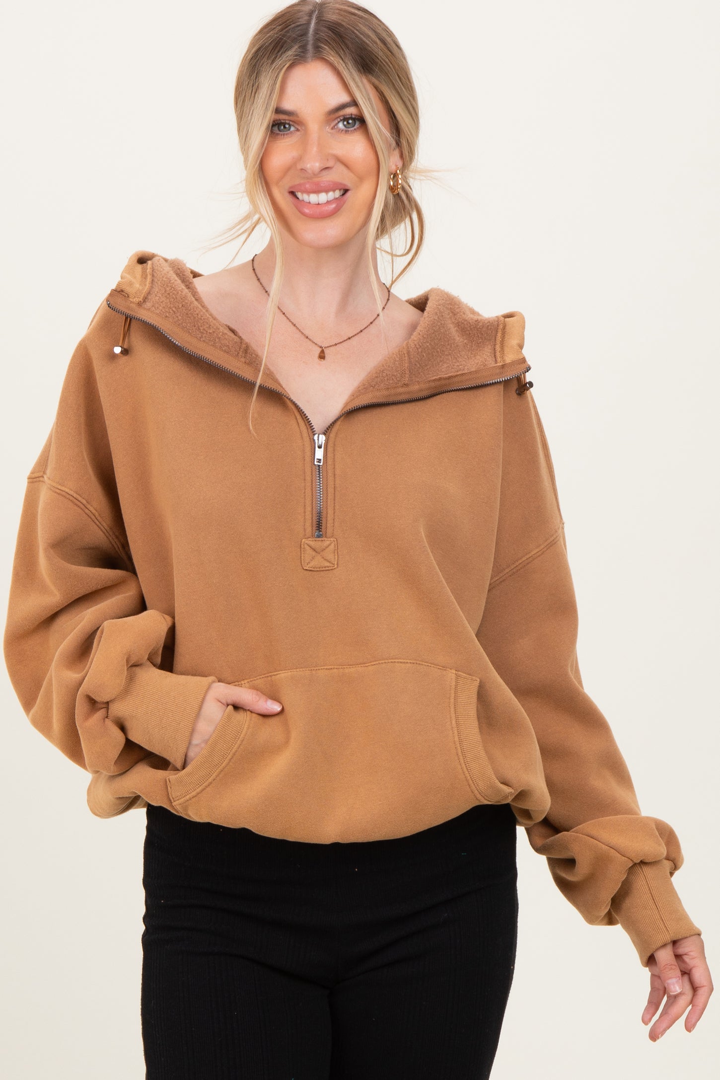 woman wearing a brown zip-up hoodie with a cozy lining and a front pocket, smiling at the camera