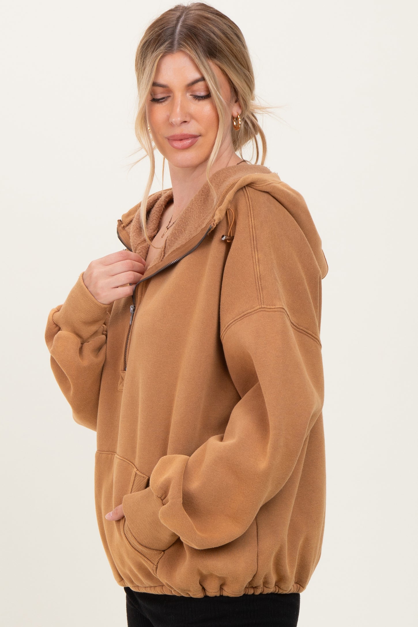 woman wearing a brown zip-up oversized hoodie with a fluffy interior and a drawstring hood