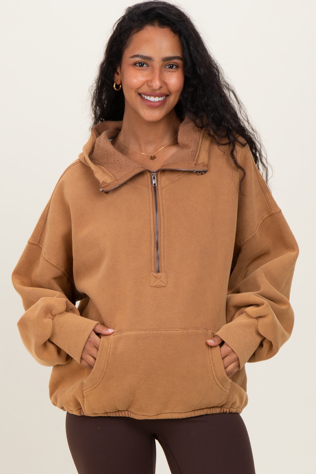 woman wearing a tan maternity pullover hoodie with a half-zip and front pockets