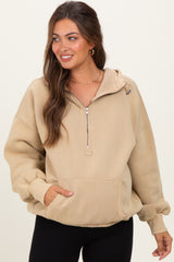 woman wearing a beige zip-up maternity hoodie with a front pocket and relaxed fit