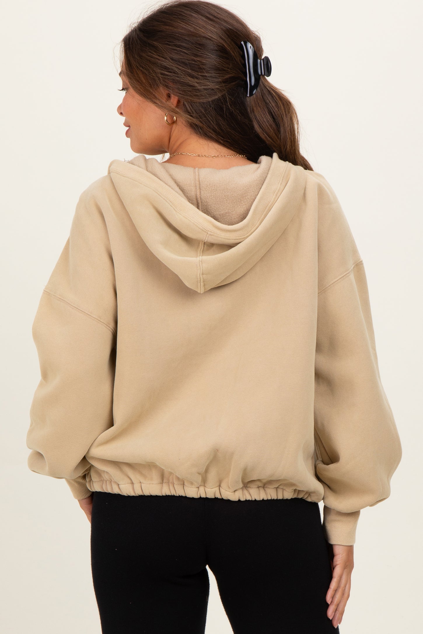 woman wearing a beige cropped maternity hoodie with a drawstring hem and hoodie detail