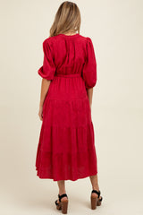 woman wearing a red tiered maternity dress with puff sleeves and a cinched waist, showing her baby bump from the back