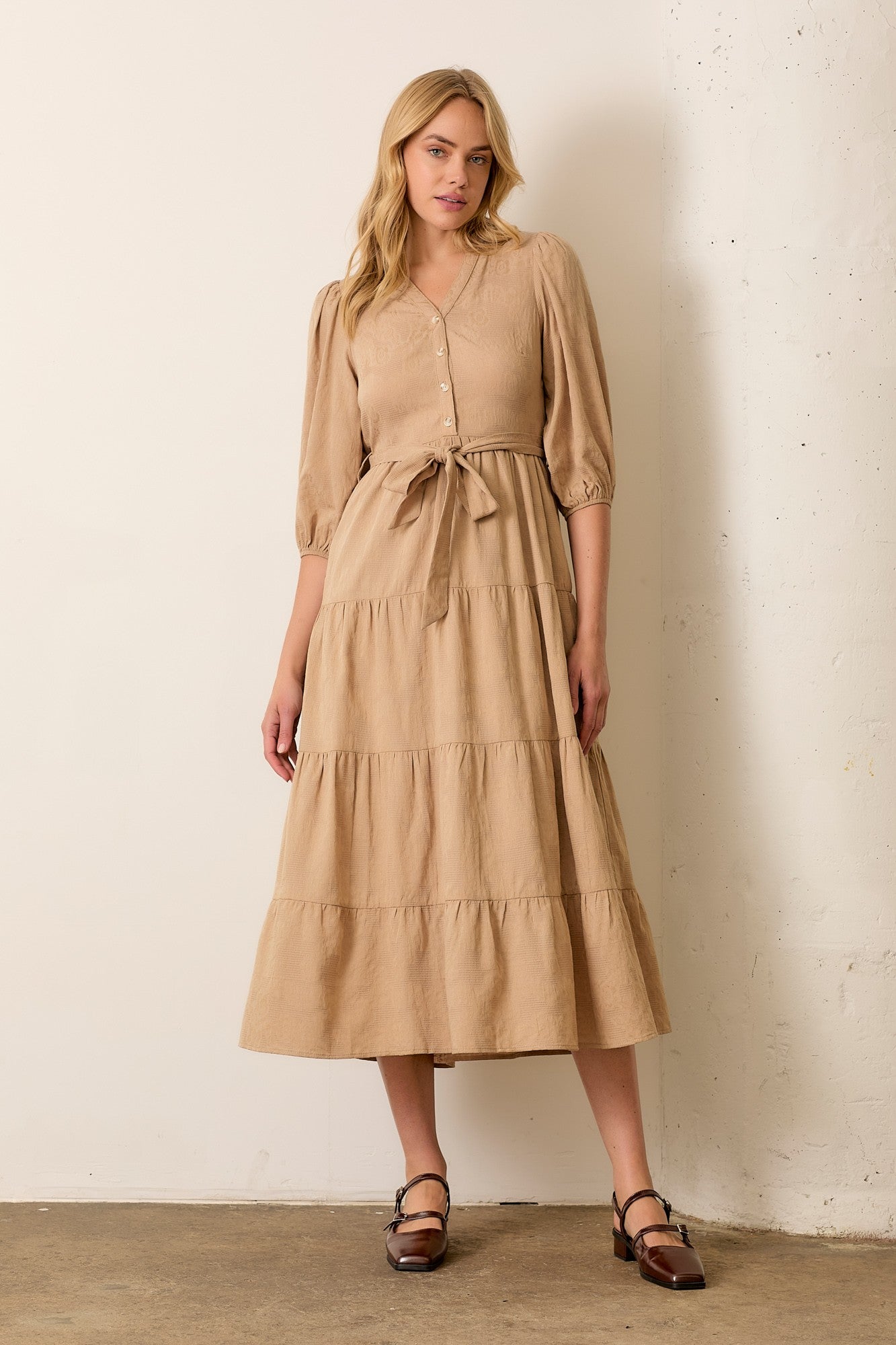 woman wearing a beige tiered maxi dress with short puff sleeves and a tie waist detail