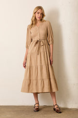 woman wearing a beige tiered maxi dress with short puff sleeves and a tie waist detail