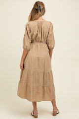 woman wearing a beige maternity tiered midi dress with puff sleeves and a tie waist, showing her baby bump from the back