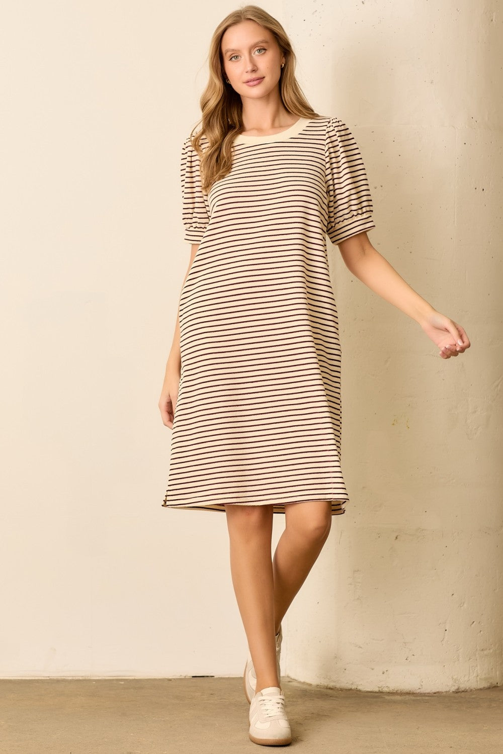 woman wearing a beige and brown striped short sleeve dress with puffed sleeves and a relaxed fit