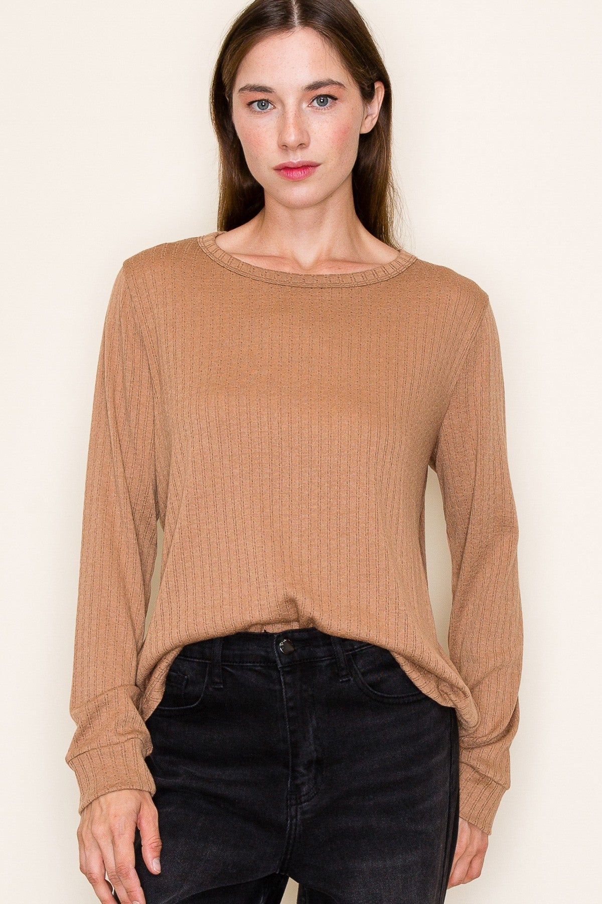 woman wearing a camel ribbed long sleeve top paired with black jeans