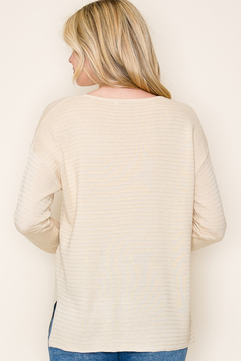 woman wearing a cream-colored striped long sleeve top, viewed from the back, paired with blue jeans