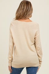 woman wearing a beige long sleeve maternity sweater with a relaxed fit, seen from the back