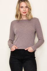 woman wearing a taupe long sleeve top with a relaxed fit and pockets, paired with black high-waisted pants