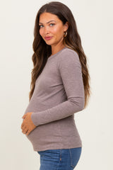 woman wearing a taupe long sleeve maternity top and holding her baby bump