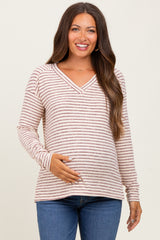 woman wearing a striped long sleeve maternity top and holding her baby bump