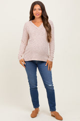 woman wearing a striped long sleeve maternity top with a v-neck and baby bump, paired with blue jeans and brown flats