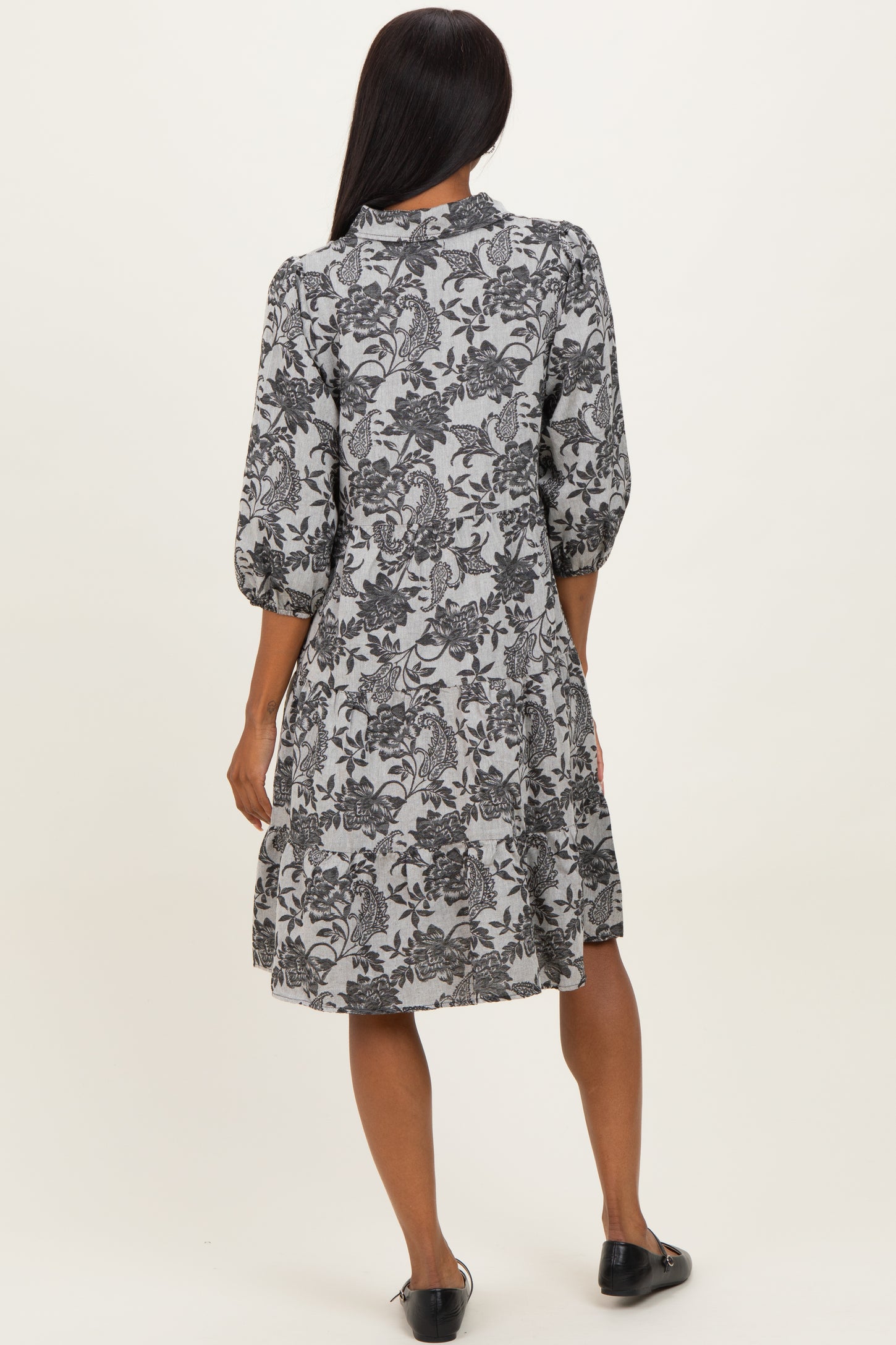 woman wearing a black and white floral print dress with three-quarter sleeves, seen from the back