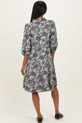 woman wearing a black and white floral print dress with three-quarter sleeves, seen from the back