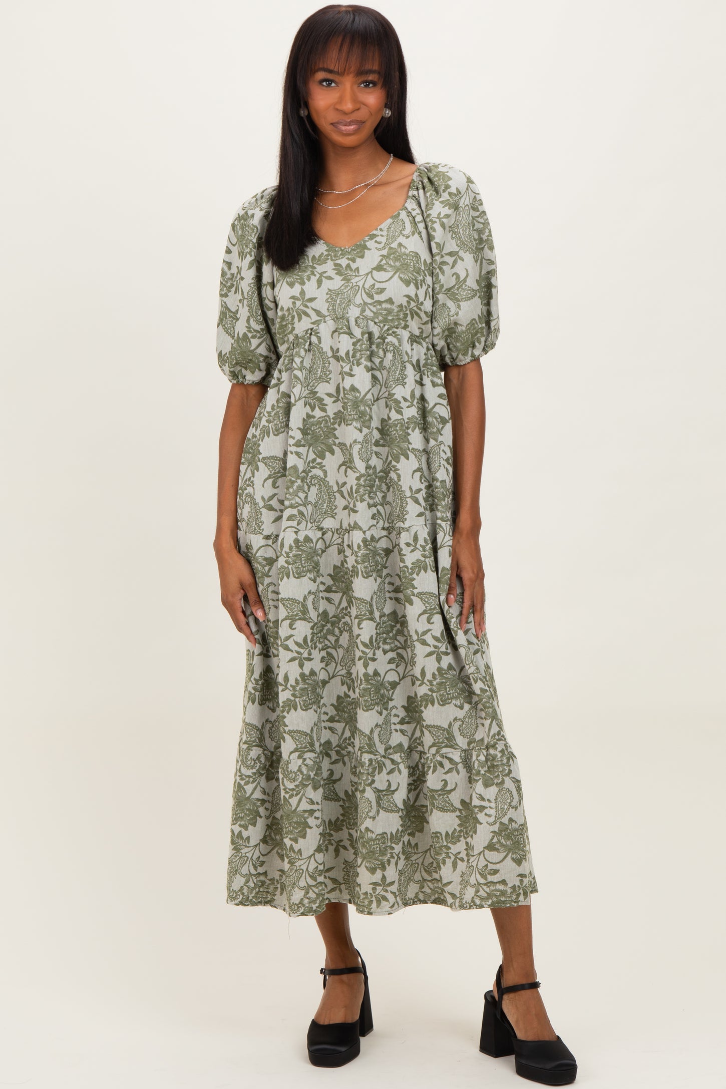 woman wearing a floral green midi dress with puff sleeves and a relaxed fit