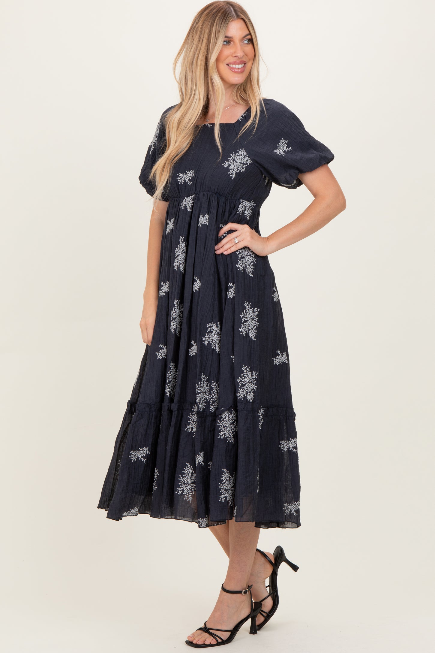 woman wearing a navy blue floral print maxi dress with puff sleeves and a tiered skirt