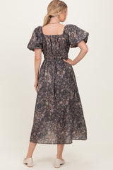 woman wearing a dark floral maxi dress with puff sleeves and an elastic waist, viewed from the back