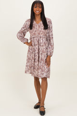 woman wearing a dusty pink floral smocked dress with long sleeves and a v-neckline