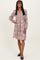 woman wearing a dusty pink floral smocked dress with long sleeves and a v-neckline
