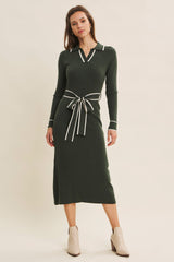 woman wearing a dark green ribbed midi dress with a collar and contrast tie at the waist, styled with ankle boots
