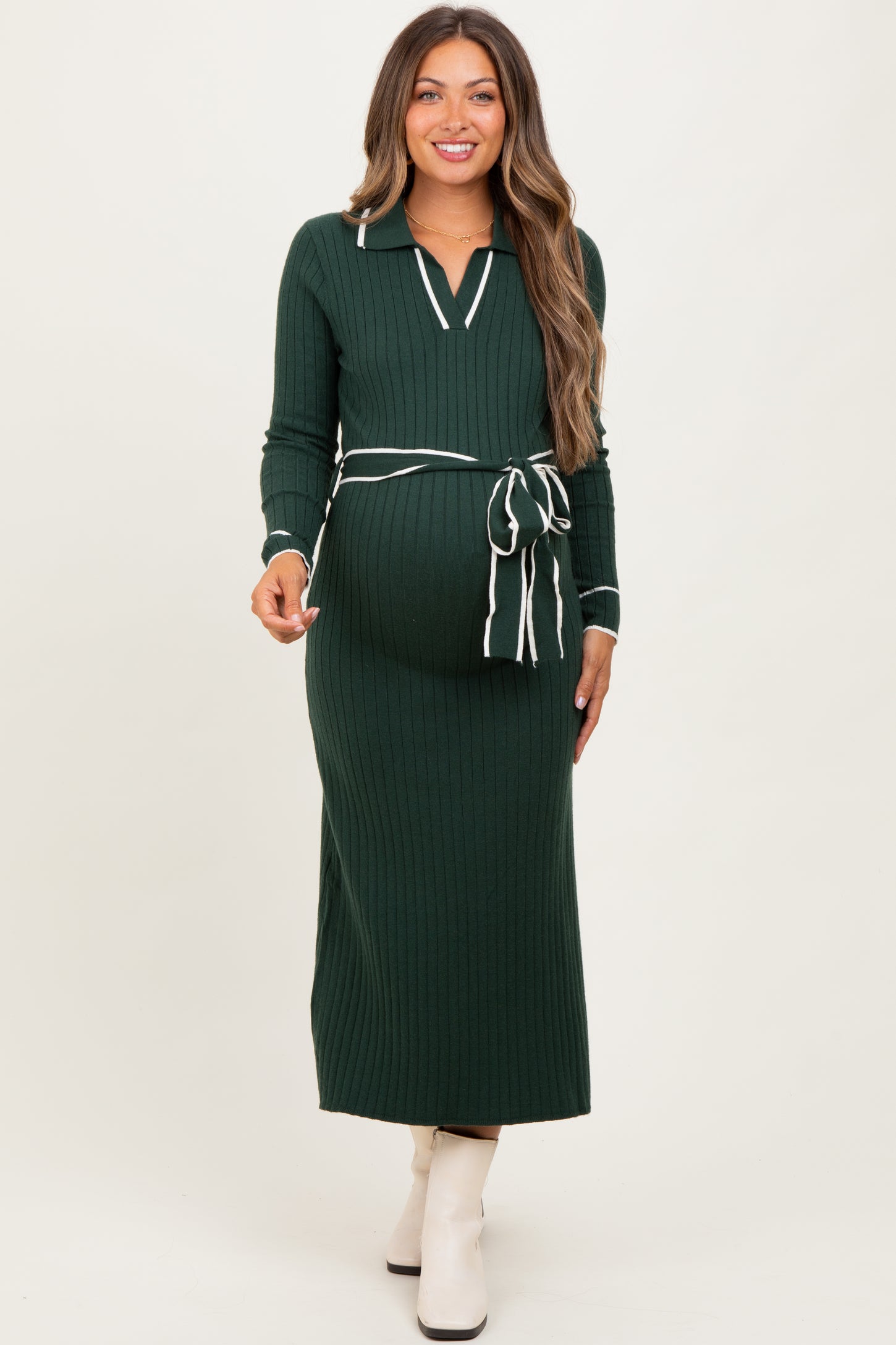 woman wearing a dark green ribbed maternity dress with a tie belt and white stripes, showing her baby bump