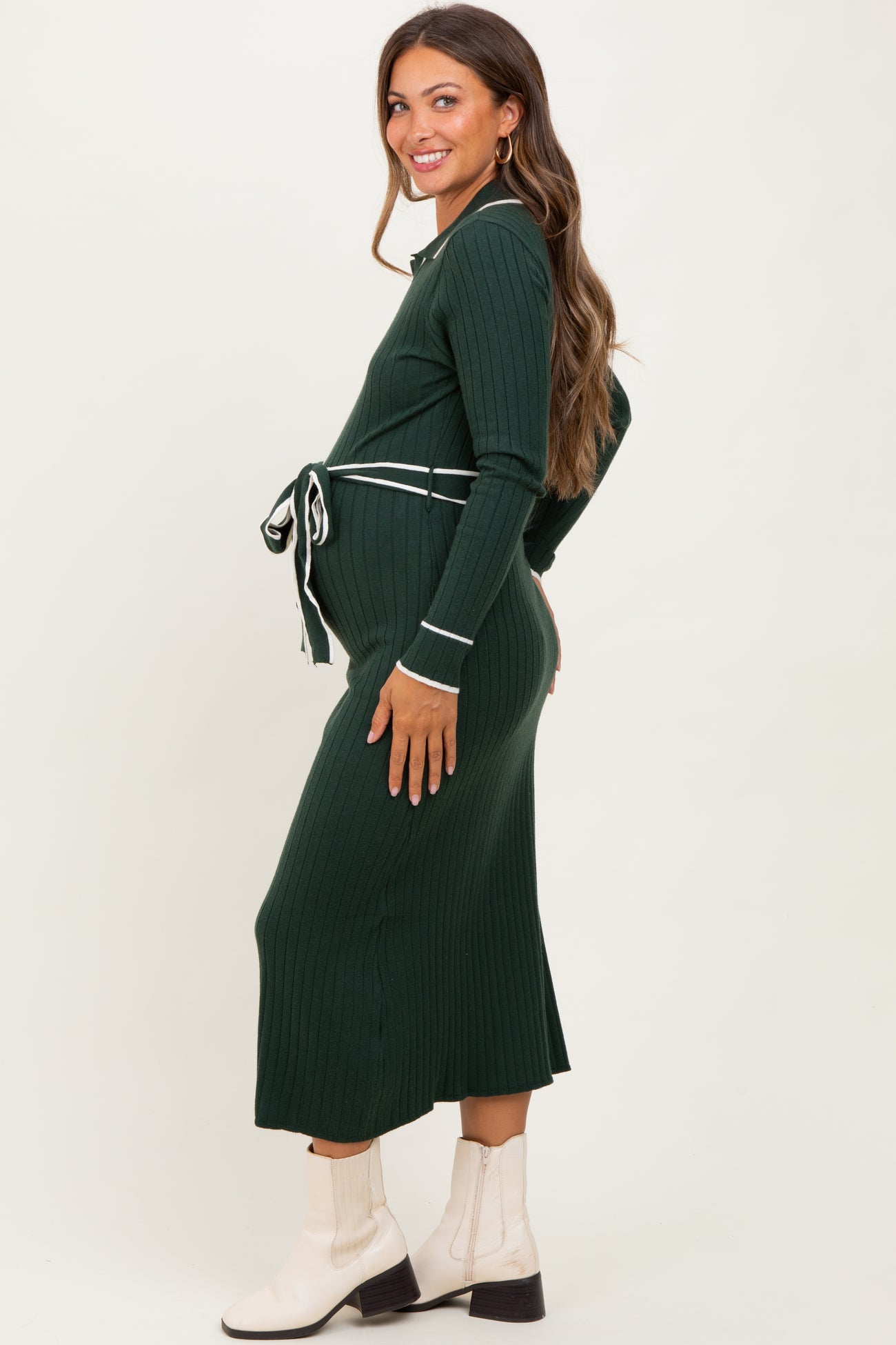 woman wearing a dark green ribbed maternity dress with a tie waist, showcasing her baby bump