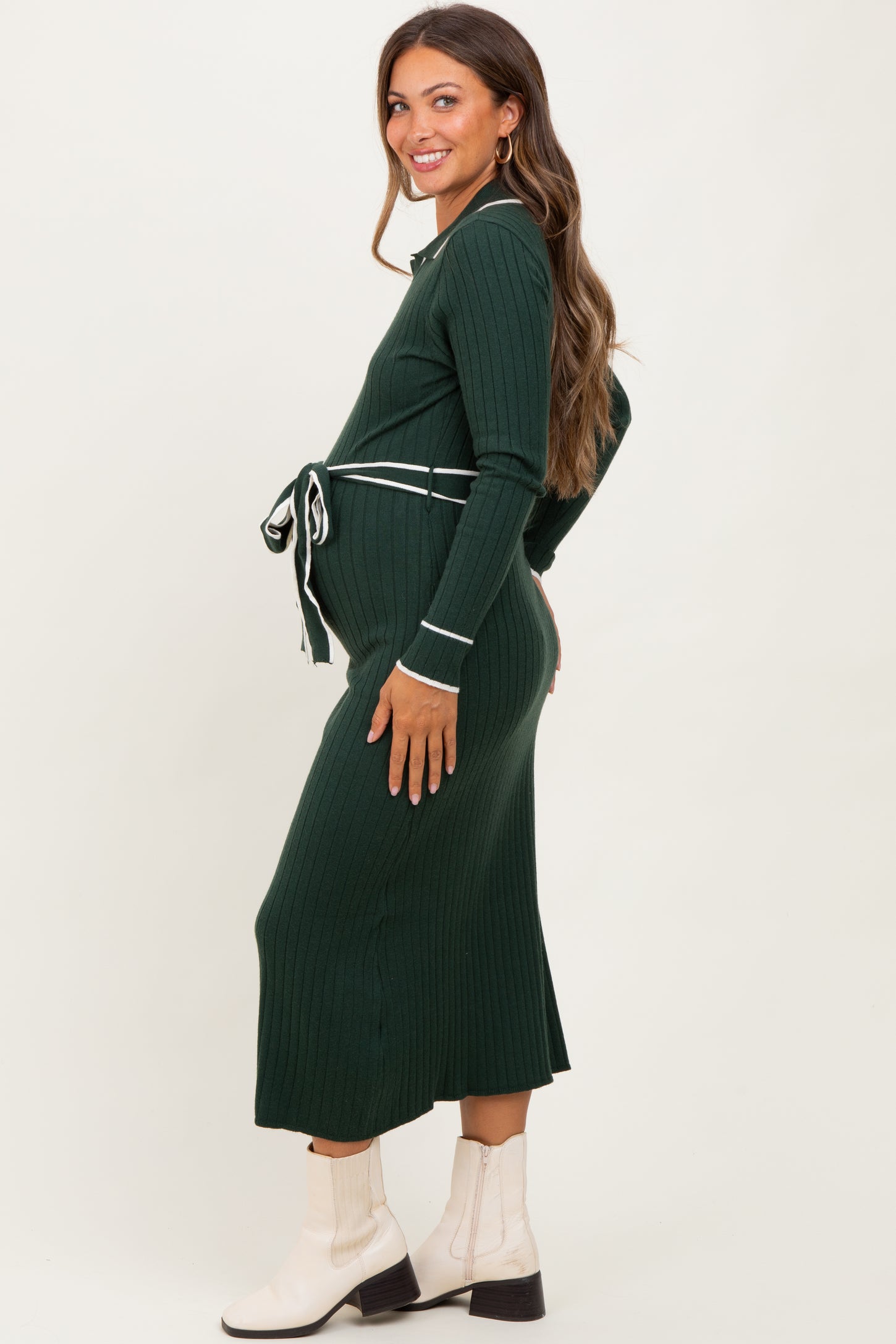 woman wearing a dark green ribbed maternity dress with a tie waist, showcasing her baby bump