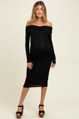woman wearing a black off-the-shoulder maternity dress with long sleeves and a baby bump visible