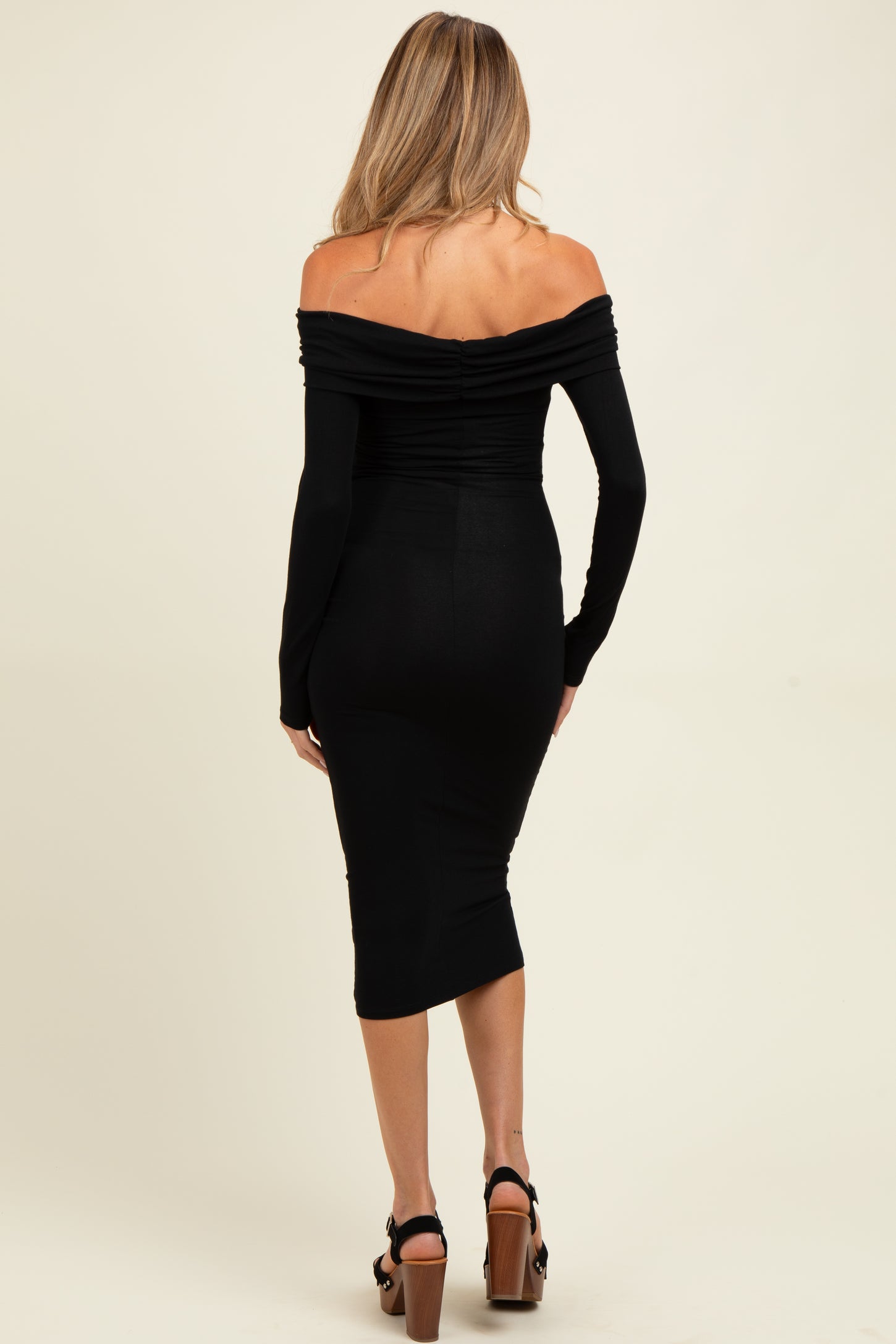 woman wearing a black off-shoulder maternity dress with long sleeves and a fitted silhouette