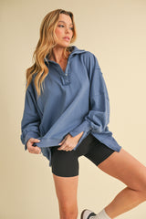 woman wearing an oversized blue pullover sweatshirt with a half zip and black biker shorts