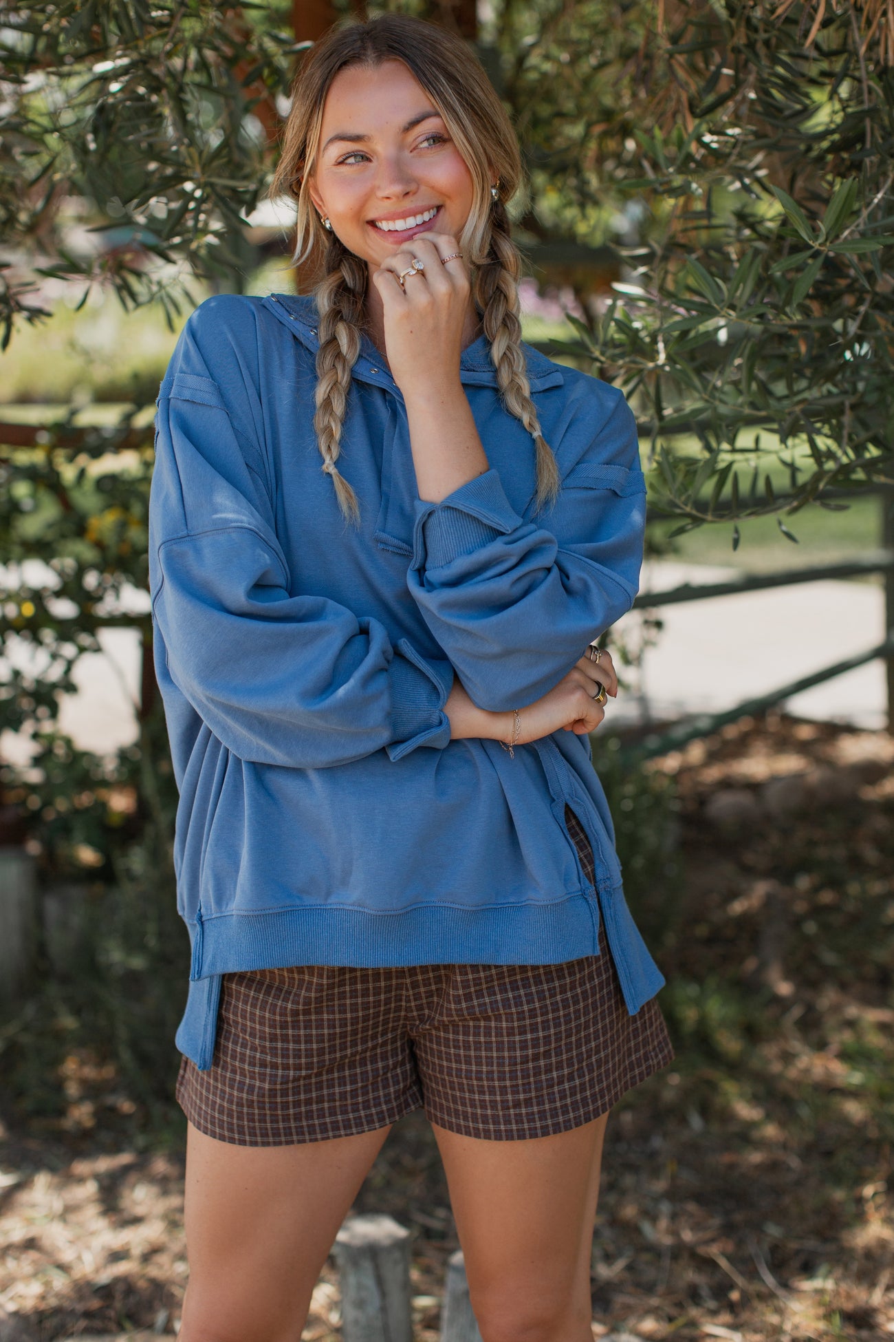 woman wearing a blue oversized hoodie with side slits and paired with brown checkered shorts