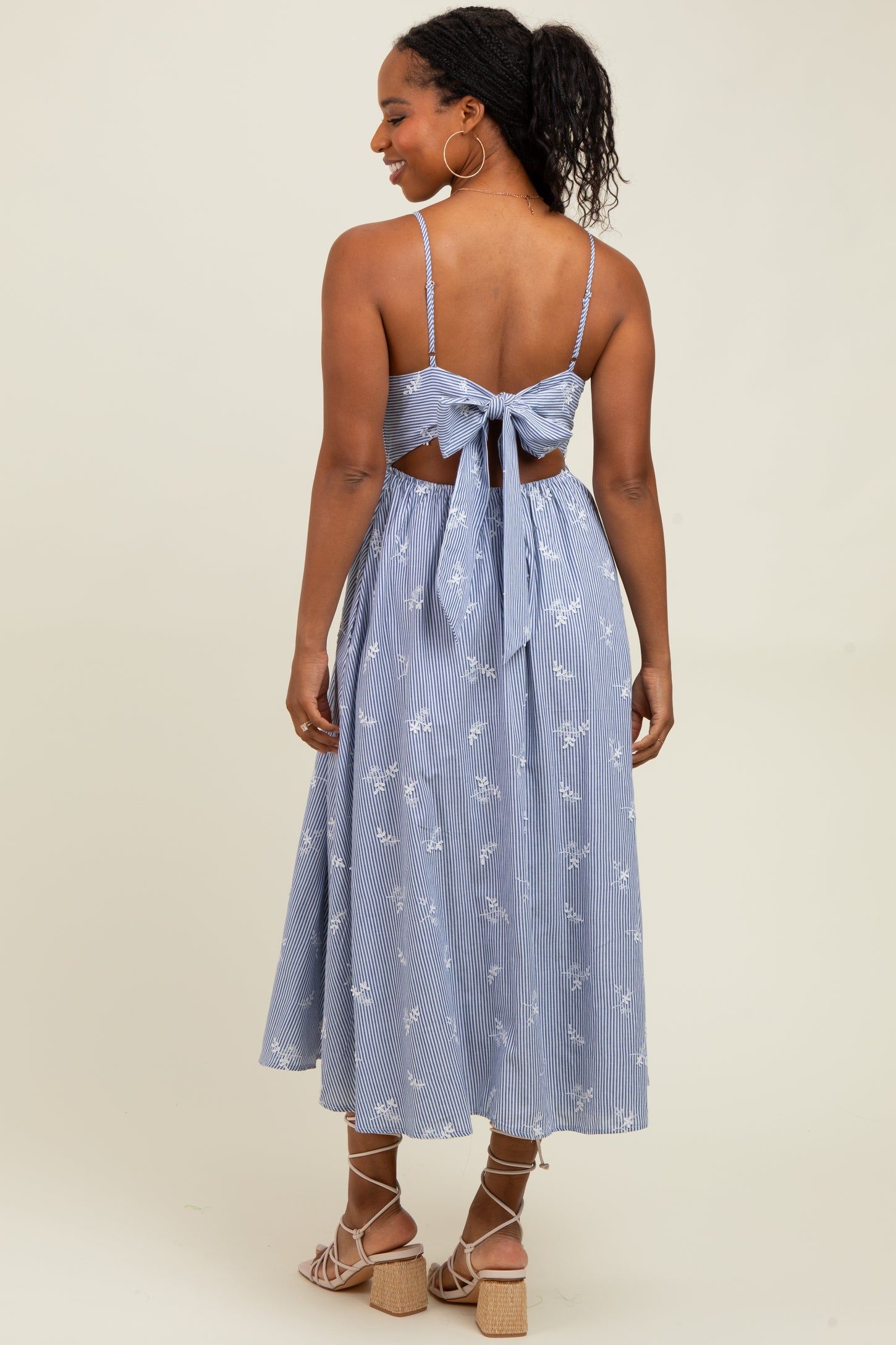 woman wearing a blue and white striped midi dress with a back tie detail and floral embroidery