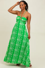 woman wearing a green maxi dress with white floral patterns and a halter neckline