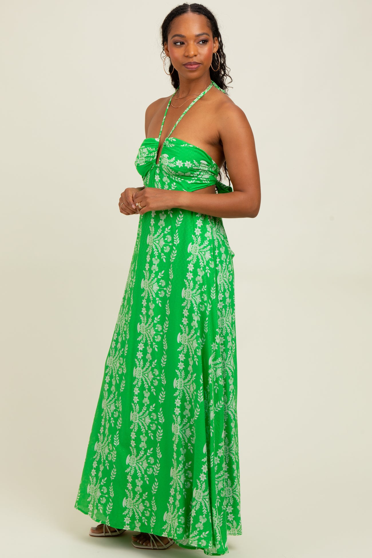 woman wearing a green floral maxi dress with a halter neck and a fitted bodice