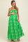 woman wearing a green halter neck maternity maxi dress with a floral pattern and holding her baby bump