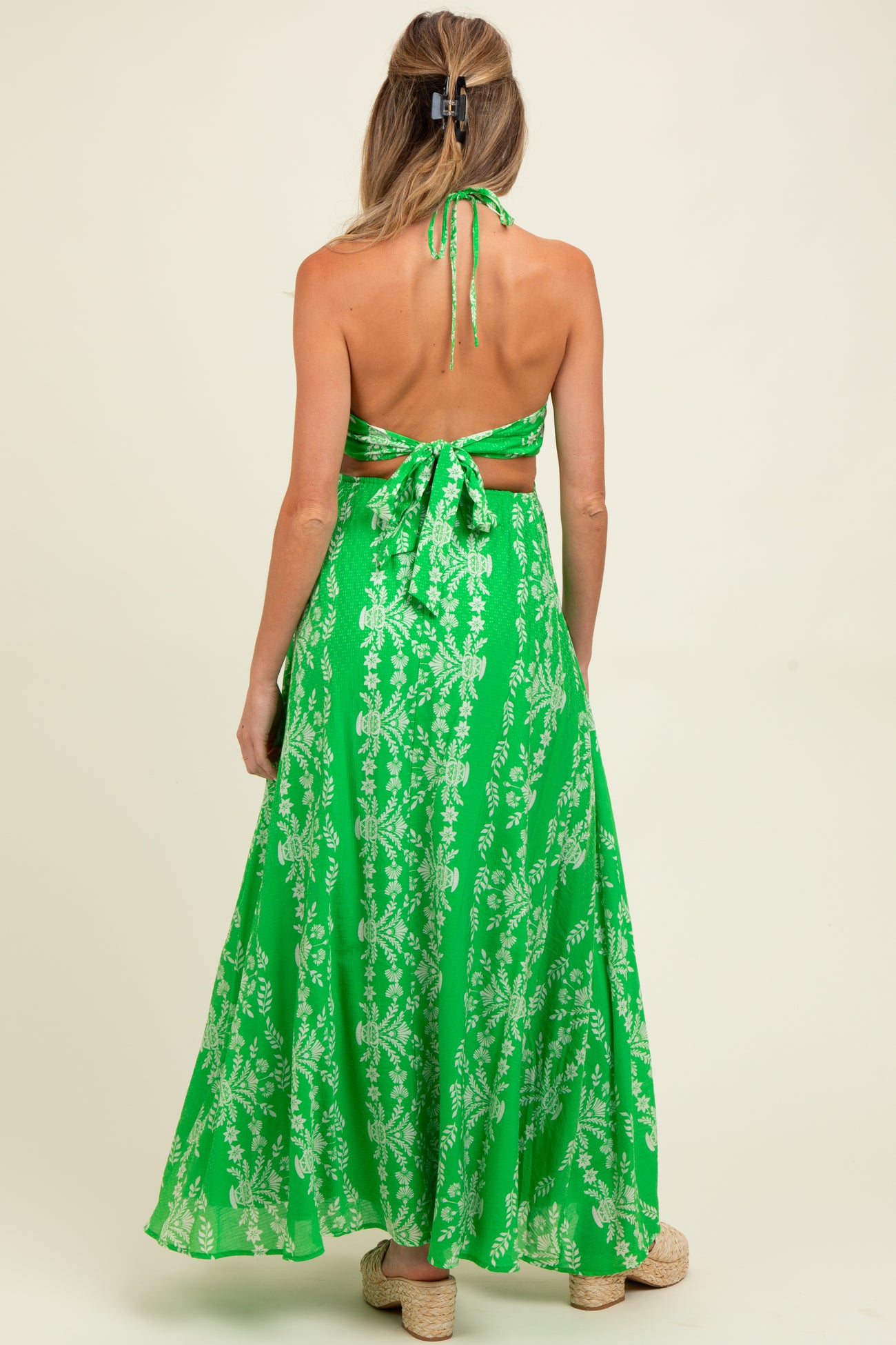 woman wearing a green floral maternity maxi dress with open back and halter neckline