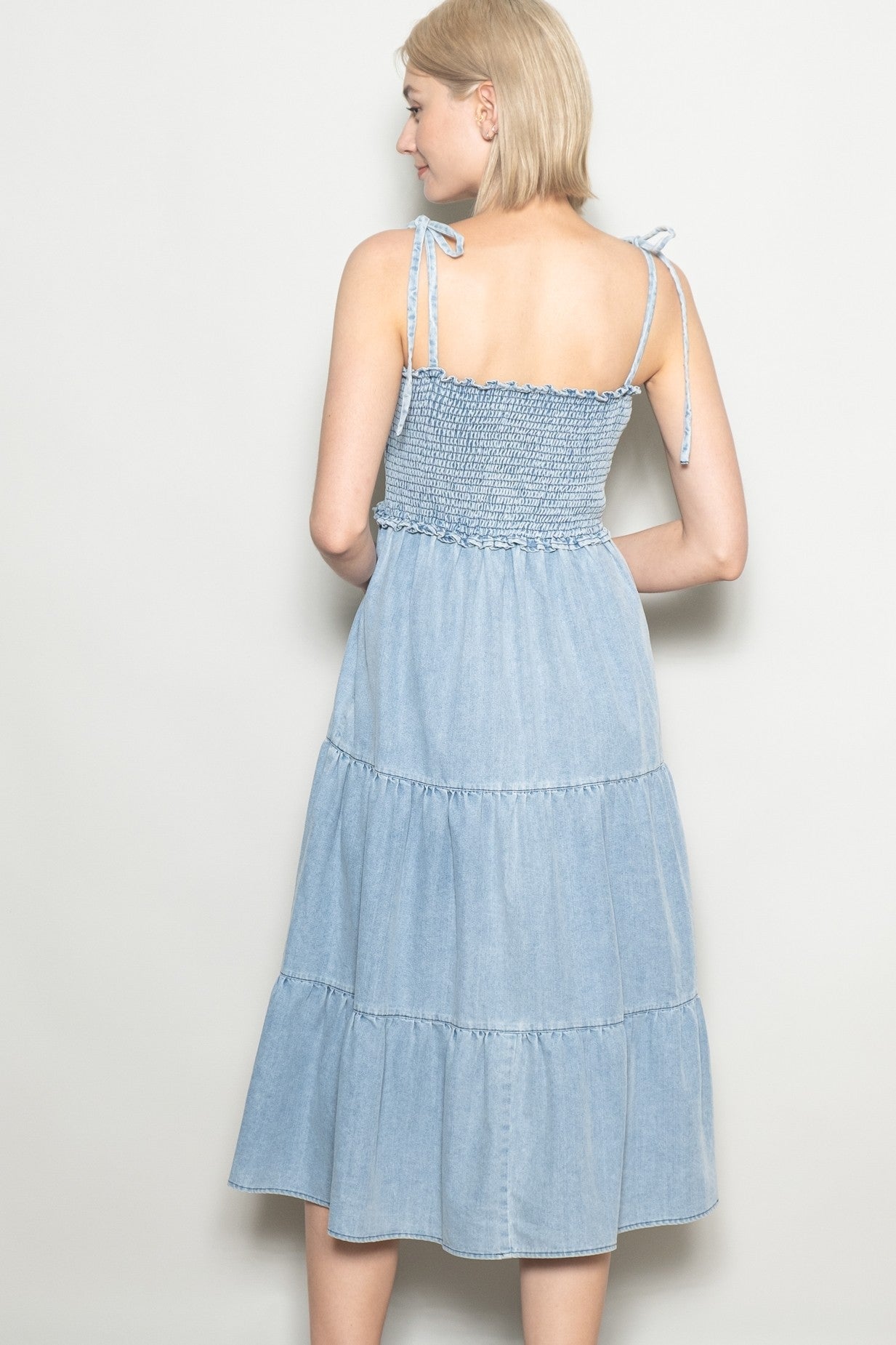 woman wearing a light blue tiered midi dress with smocked bodice and adjustable tie straps