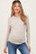 woman wearing a light beige ribbed maternity top and blue jeans with a visible baby bump