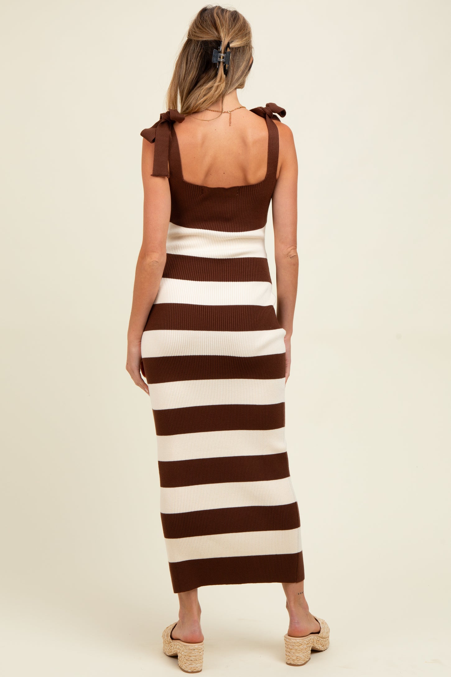 woman wearing a brown and cream striped maternity dress with shoulder tie details and a fitted silhouette