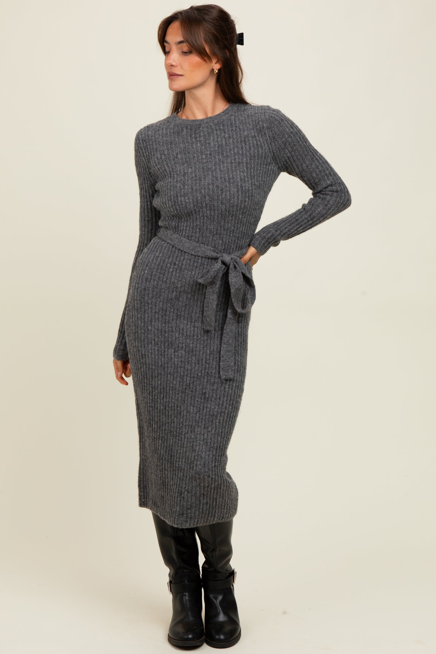 woman wearing a gray ribbed knit long sleeve dress with a belted waist and black knee-high boots