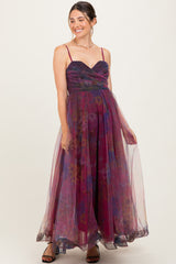 woman wearing a purple floral maternity dress with a flowy skirt and spaghetti straps, showcasing her baby bump